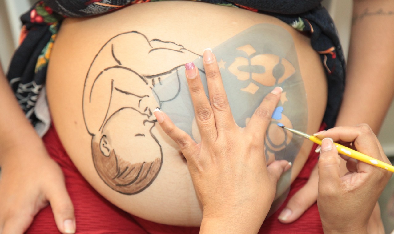 enfermeira desenhando um bebê na barriga de uma mulher grávida